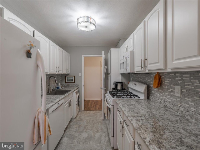 kitchen with white appliances, a sink, white cabinets, tasteful backsplash, and a textured ceiling