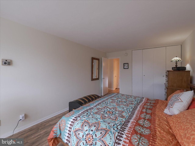 bedroom with wood finished floors, a closet, and baseboards