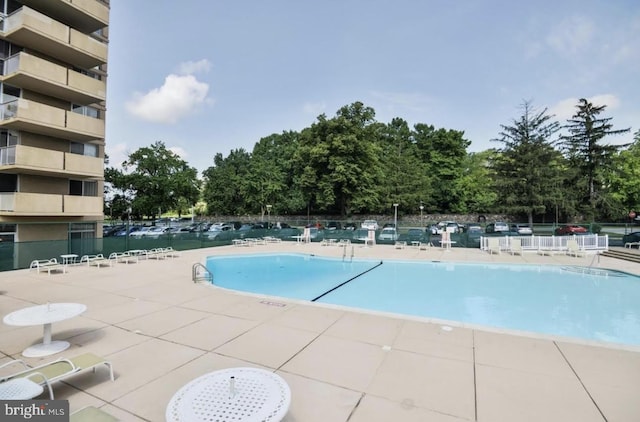 community pool with fence and a patio