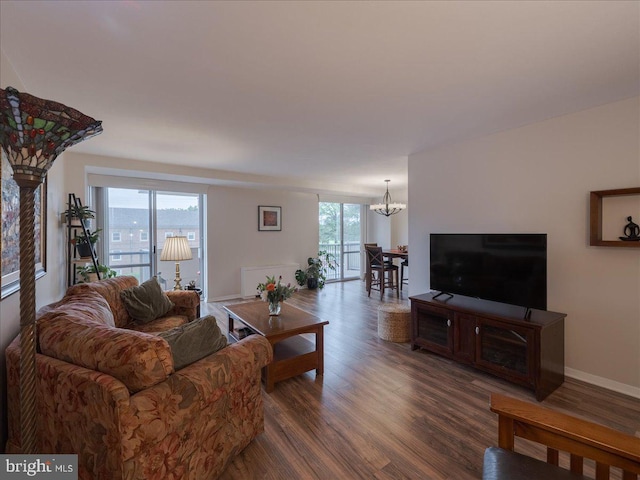 living area with a chandelier, dark wood-type flooring, and baseboards