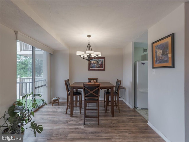 dining area with a chandelier, wood finished floors, and baseboards