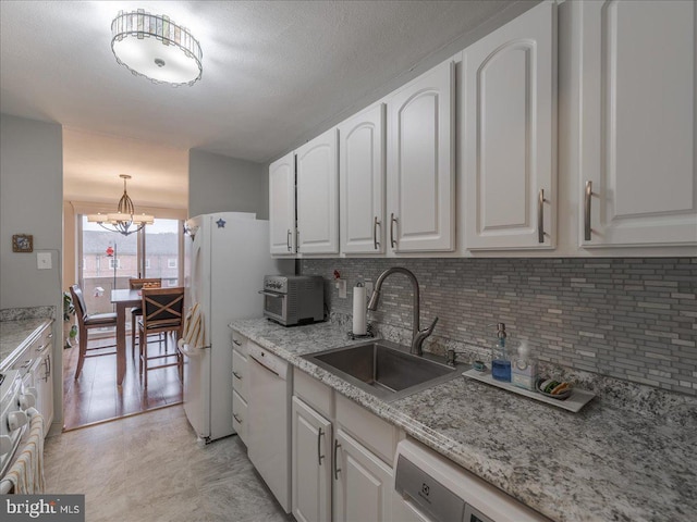kitchen with a sink, white dishwasher, a chandelier, tasteful backsplash, and white cabinets