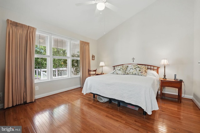 bedroom featuring wood-type flooring, baseboards, high vaulted ceiling, and a ceiling fan