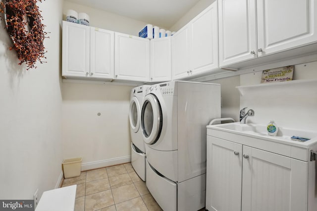 laundry room featuring separate washer and dryer, baseboards, cabinet space, and light tile patterned floors