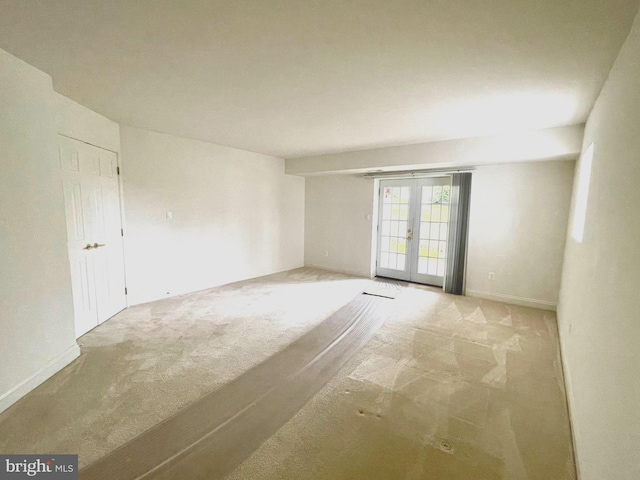 carpeted empty room featuring french doors and baseboards