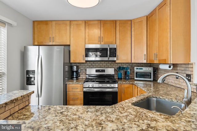 kitchen featuring stainless steel appliances, a sink, decorative backsplash, and light stone counters