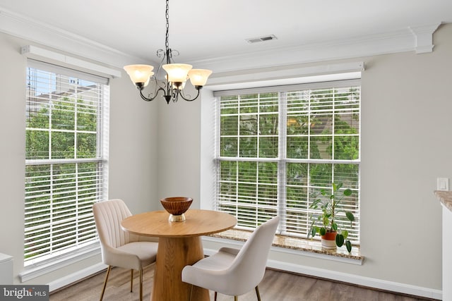 dining area with crown molding, a chandelier, healthy amount of natural light, wood finished floors, and baseboards