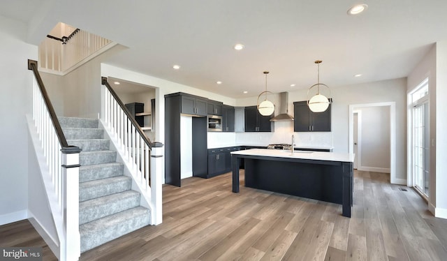 2030 N Fall Harvest Dr, Mechanicsburg, PA 17055 - kitchen with stainless steel microwave, light countertops, wall chimney exhaust hood, tasteful backsplash, and a center island with sink