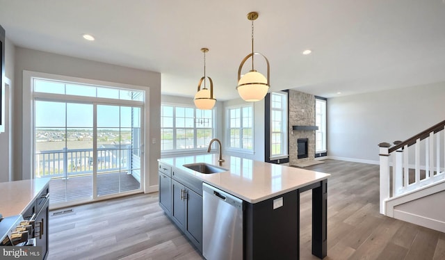 2030 N Fall Harvest Dr, Mechanicsburg, PA 17055 - kitchen featuring a sink, dishwasher, light wood-type flooring, hanging light fixtures, and a fireplace
