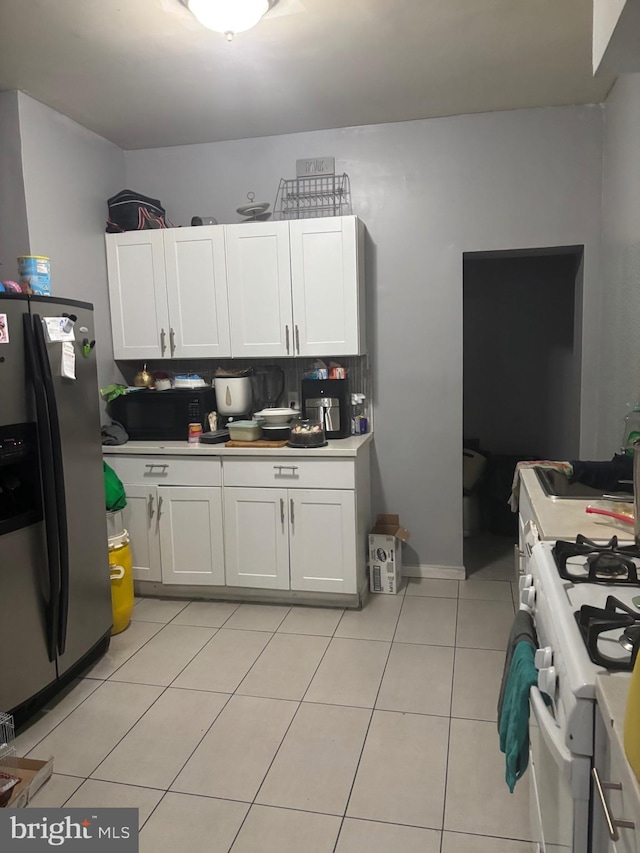 3910 N 8th St, Philadelphia, PA 19140 - kitchen with stainless steel fridge, white range with gas cooktop, white cabinetry, light tile patterned floors, and light countertops