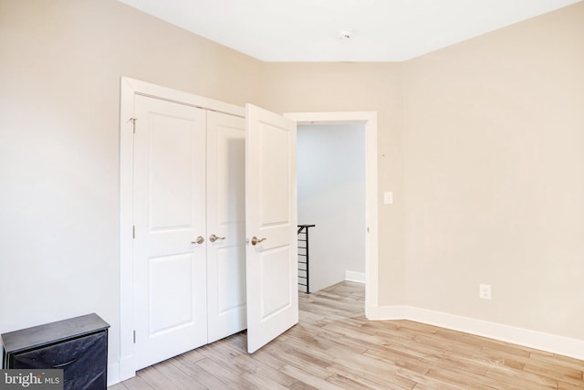 unfurnished bedroom with light wood finished floors, a closet, and baseboards
