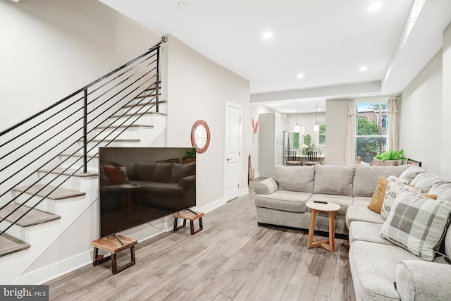 living area featuring light wood-type flooring, stairway, baseboards, and recessed lighting