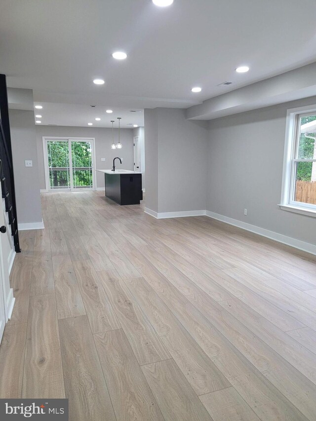 5209 10th Pl S, Arlington, VA 22204 - unfurnished living room featuring light wood-style flooring, recessed lighting, baseboards, healthy amount of natural light, and a sink