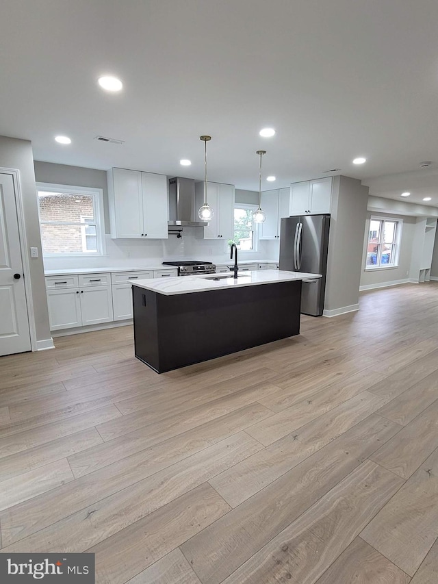 5209 10th Pl S, Arlington, VA 22204 - kitchen featuring stainless steel appliances, wall chimney range hood, light countertops, light wood-style floors, and a center island with sink