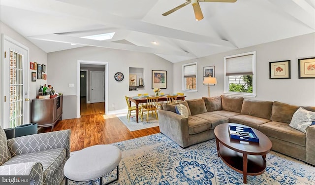 living area featuring wood finished floors, vaulted ceiling, ceiling fan, and baseboards