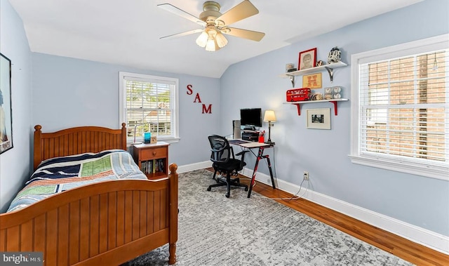 bedroom featuring wood finished floors, a desk, baseboards, and a ceiling fan