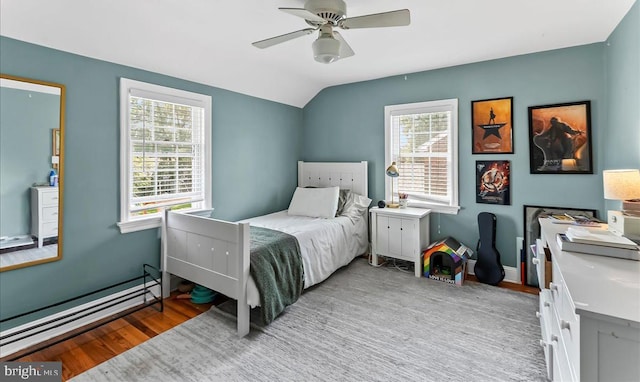 bedroom with wood finished floors, lofted ceiling, a ceiling fan, and a baseboard heating unit