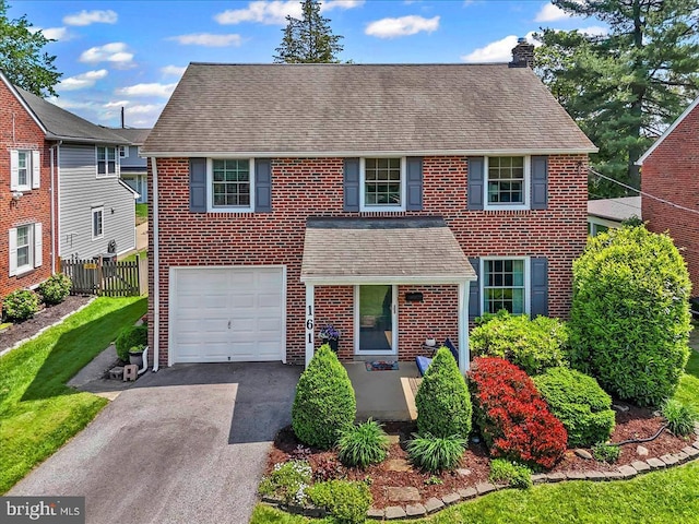 view of front of property with fence, a chimney, brick siding, and a garage