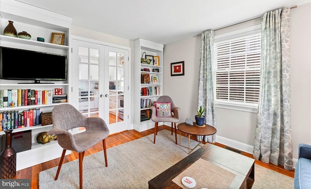 sitting room with french doors, wood finished floors, and baseboards