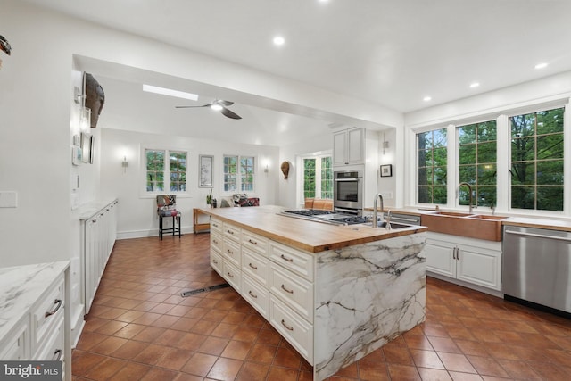 4301 Forest Ln NW, Washington, DC 20007 - kitchen featuring stainless steel appliances, a sink, wood counters, dark tile patterned floors, and a kitchen island