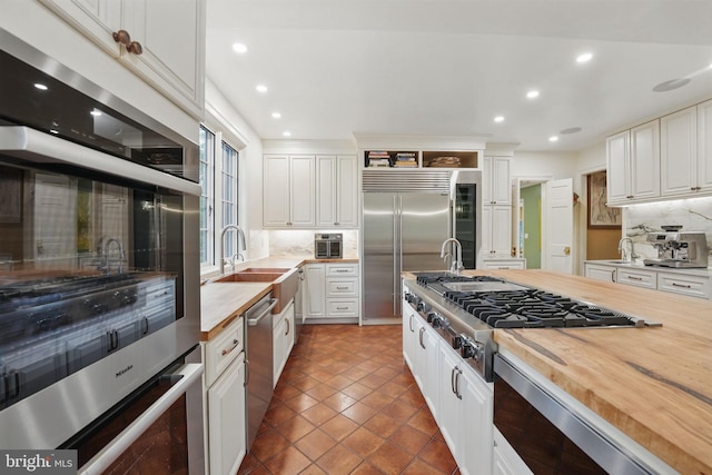 4301 Forest Ln NW, Washington, DC 20007 - kitchen with wood counters, built in appliances, a sink, decorative backsplash, and recessed lighting