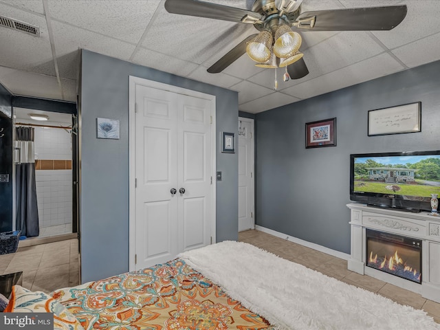 9 S Laurel Ave, Berkeley Springs, WV 25411 - tiled bedroom featuring a drop ceiling, baseboards, a glass covered fireplace, a ceiling fan, and a closet