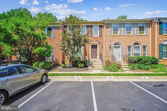 view of property featuring uncovered parking and brick siding