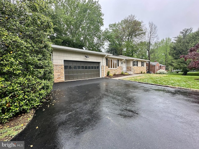 single story home featuring an attached garage, asphalt driveway, a front lawn, and stone siding