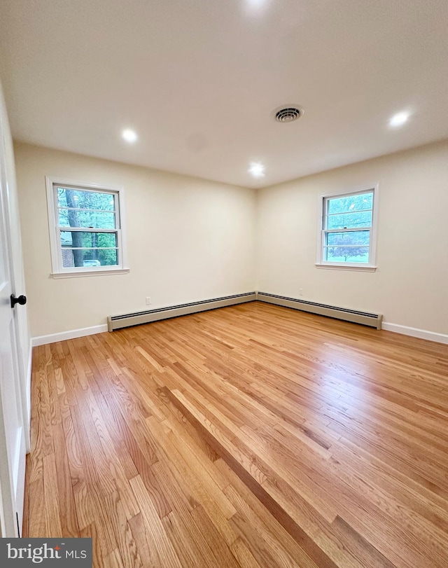 spare room featuring a baseboard radiator, wood finished floors, baseboards, and recessed lighting