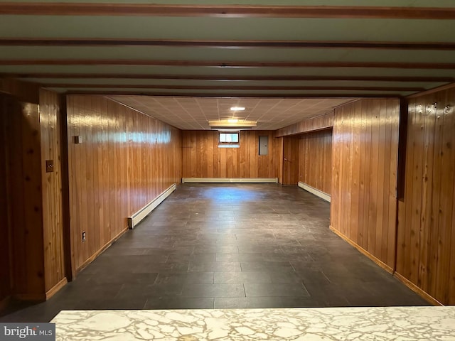 basement featuring a baseboard radiator, wooden walls, and baseboards