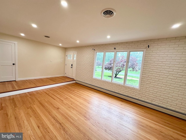 unfurnished room featuring brick wall, baseboards, wood finished floors, recessed lighting, and baseboard heating