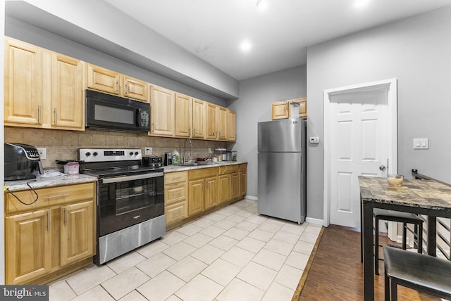 2562 N 31st St, Philadelphia, PA 19132 - kitchen featuring stainless steel appliances, light brown cabinetry, backsplash, light stone counters, and light tile patterned flooring