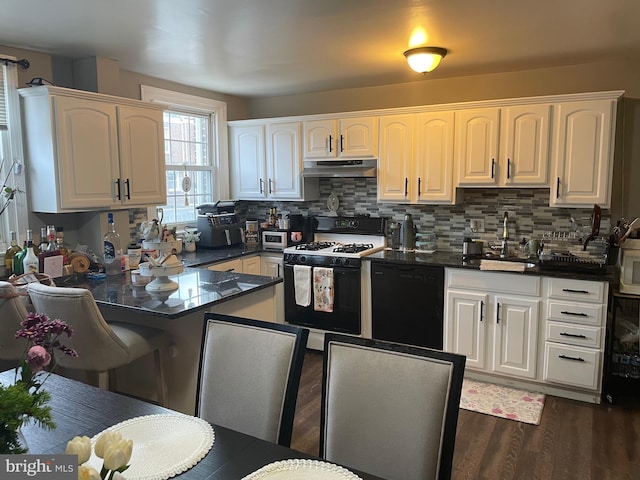 3110 Wellington St, Philadelphia, PA 19149 - kitchen with range with gas stovetop, black dishwasher, under cabinet range hood, and dark countertops