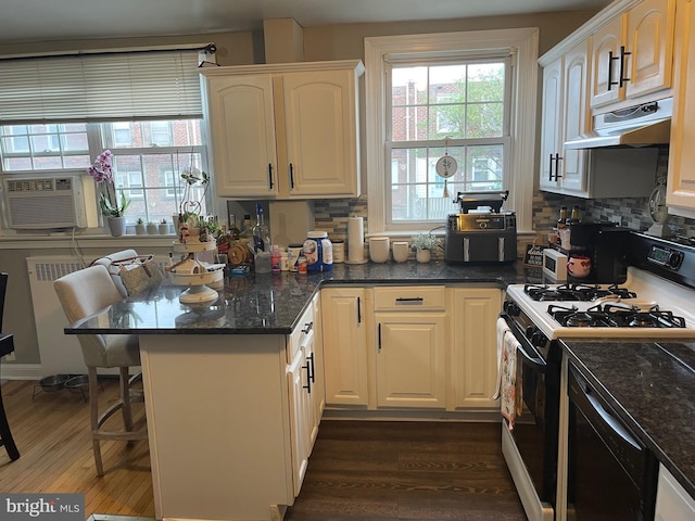 3110 Wellington St, Philadelphia, PA 19149 - kitchen featuring gas range, under cabinet range hood, dark wood-type flooring, a peninsula, and a kitchen bar
