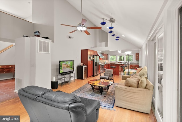 living room featuring high vaulted ceiling, a ceiling fan, and light wood-style flooring