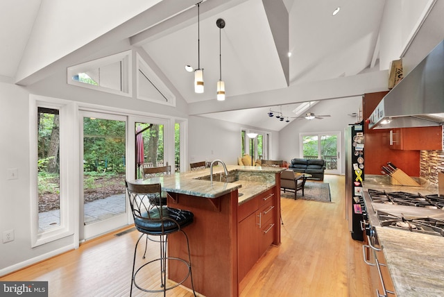 kitchen featuring stainless steel appliances, high vaulted ceiling, open floor plan, a kitchen breakfast bar, and brown cabinets