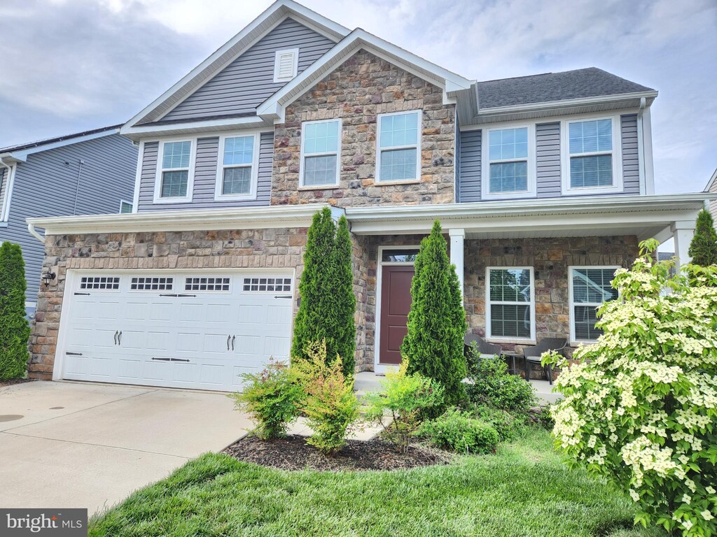 craftsman house with stone siding, driveway, and an attached garage