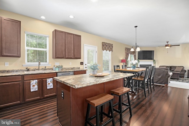 kitchen featuring a sink, dark wood-type flooring, a center island, ceiling fan, and a breakfast bar area