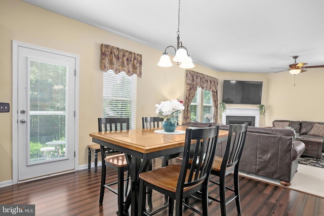 dining area with dark wood finished floors, a fireplace, a chandelier, and ceiling fan