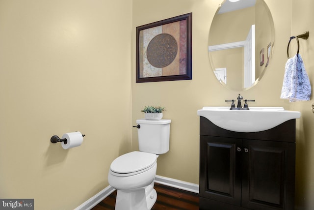 bathroom featuring wood finished floors, baseboards, toilet, and vanity