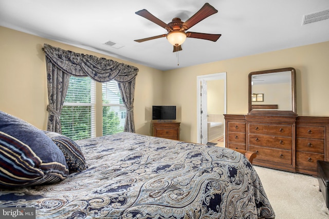 carpeted bedroom featuring a ceiling fan and ensuite bath