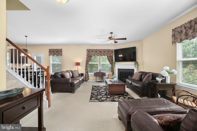 living room featuring stairs, carpet, a ceiling fan, and a fireplace