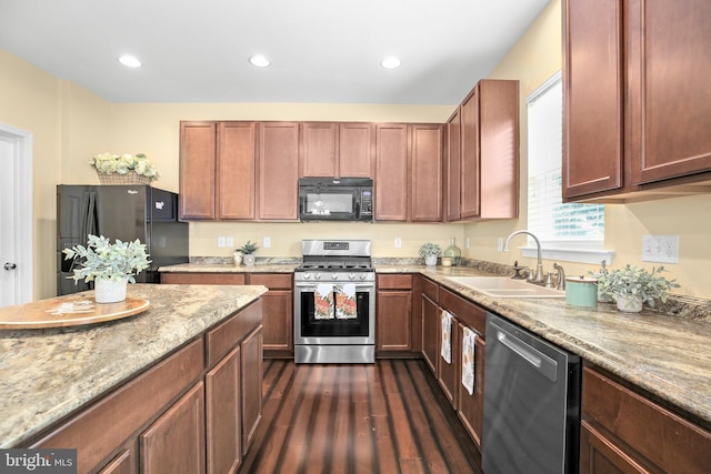 kitchen with black appliances, a sink, dark wood-type flooring, light stone counters, and recessed lighting