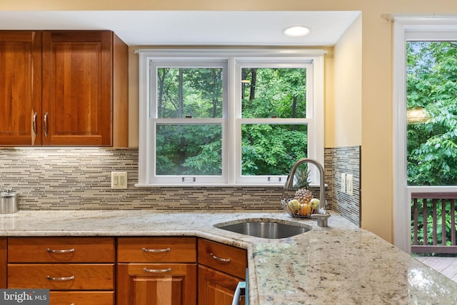 5212 Braywood Dr, Centreville, VA 20120 - kitchen featuring a sink, light stone counters, brown cabinets, and decorative backsplash