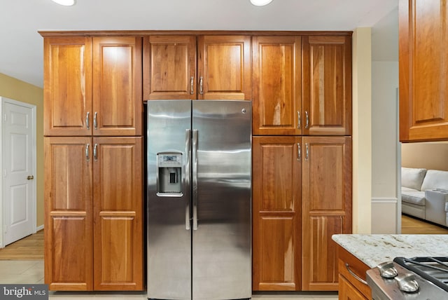5212 Braywood Dr, Centreville, VA 20120 - kitchen featuring stainless steel fridge with ice dispenser, brown cabinetry, light stone counters, and stove