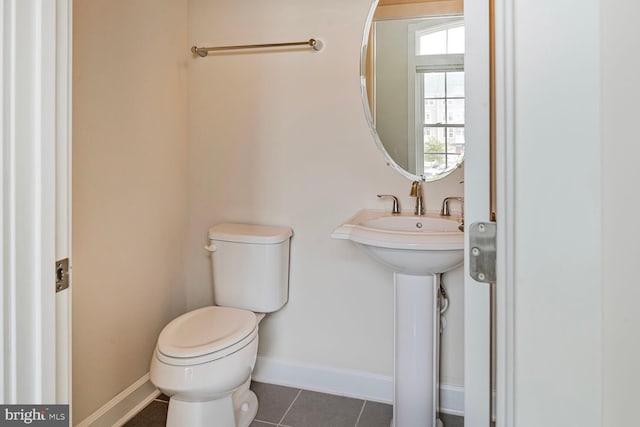 half bathroom with toilet, tile patterned floors, and baseboards