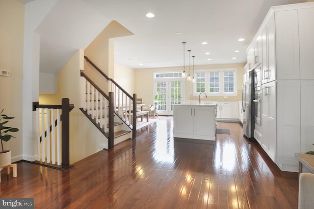 kitchen featuring dark wood finished floors, a sink, an island with sink, freestanding refrigerator, and white cabinets