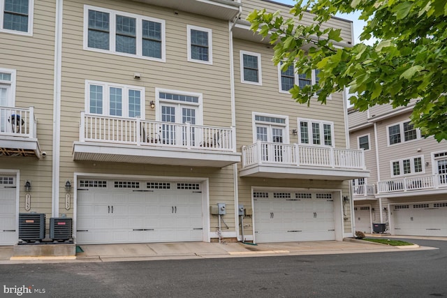 back of property with central AC unit and a garage