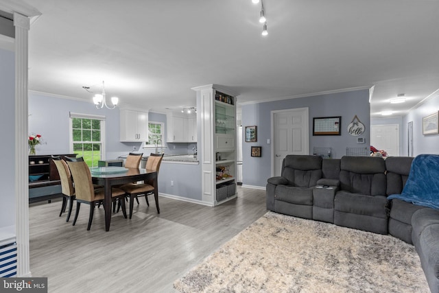 living area featuring light wood-type flooring, ornamental molding, and a chandelier
