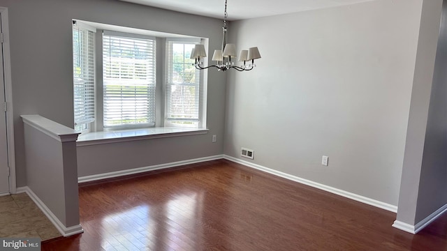 unfurnished dining area featuring a chandelier, wood finished floors, and baseboards